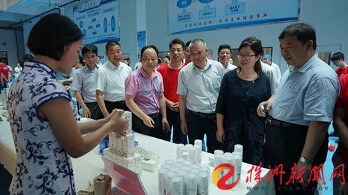副厅长应若平在化妆品展示台前观看，与学生交谈，了解产教融合情况。